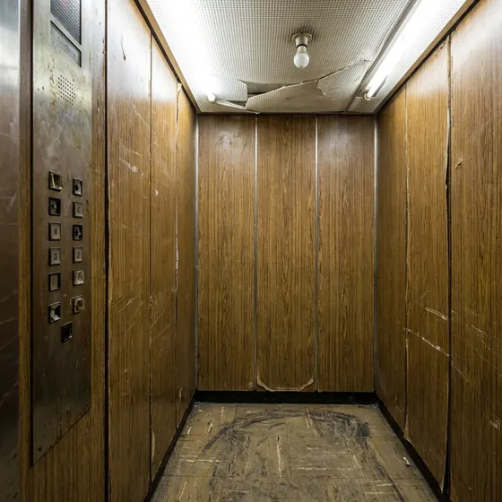 Tired lift cab interior with worn flooring and dated wall finishes — typical aesthetics problem on a 20+ year old lift