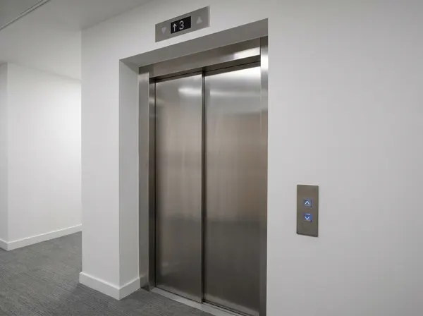 Modernised lift landing doors — brushed stainless steel with vision panel and current safety circuit interlocks